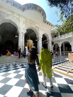 a man and woman walking in front of a white building with black and white checkered floor