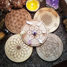 four wooden coasters sitting on top of a table next to rocks and crystals with candles in the background