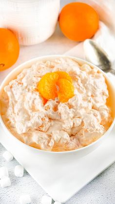 there is a bowl of oatmeal with oranges on the table next to it