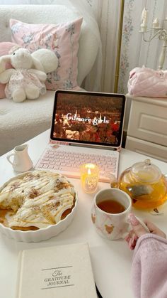 a laptop computer sitting on top of a white table next to a cup of tea