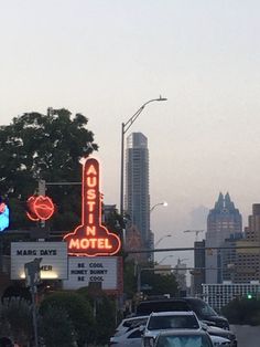 cars are driving down the street in front of motels and neon signs at dusk