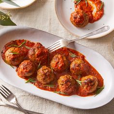 meatballs covered in marinara sauce and garnished with herbs on a white plate