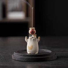 a small figurine with a incense stick in it's mouth on a black surface