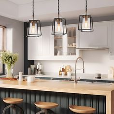 three lights hanging over a kitchen island with stools