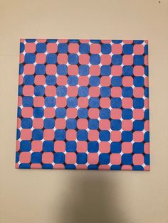 a blue and pink square with white dots on the top is hanging from a wall