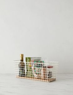 a white basket filled with food on top of a counter next to a wine bottle