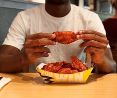 a man sitting at a table with food in front of him and his hands on the plate