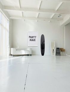 an empty room with white walls and black surfboard on the floor in front of it