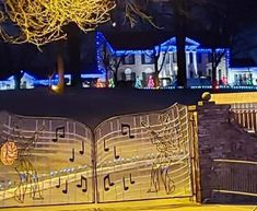 an open gate with musical notes on it and christmas lights in the background at night