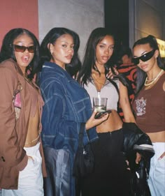 four women are posing for the camera with one holding a wine glass in her hand