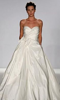 a woman in a white wedding dress walking down the runway