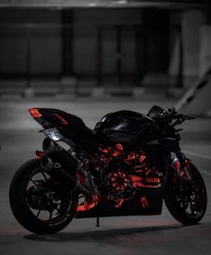 a black and red motorcycle parked in a parking lot with its lights on at night