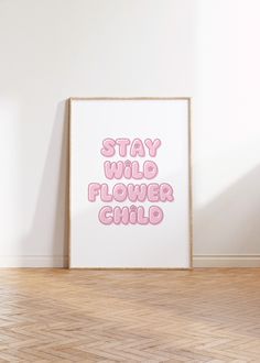 a pink poster with the words stay wild, flower child on it in front of a white wall