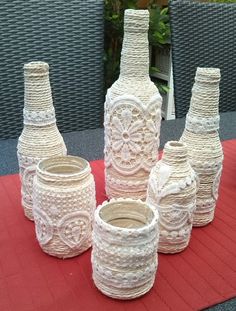 four white vases sitting on top of a red table