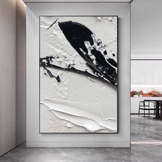 an abstract black and white painting hangs on the wall next to a dining room table