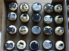 a box filled with cupcakes covered in white frosting and black icing