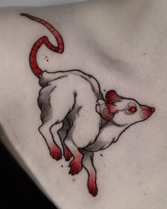 a rat tattoo on the back of a woman's shoulder and chest, with red eyes