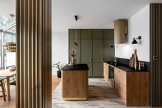 a kitchen with wooden cabinets and black counter tops next to a dining room table in front of a glass wall