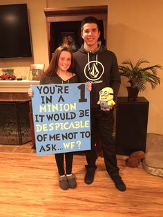 a man and woman standing next to each other holding a sign that says you're in a minion it would be despicable if not to ask me not to ask wf?