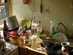 cluttered kitchen counter with pots and pans on it