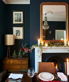 the dining room table is set for dinner with candles and flowers in front of it