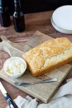 a loaf of bread sitting on top of a cutting board next to a bowl of ice cream