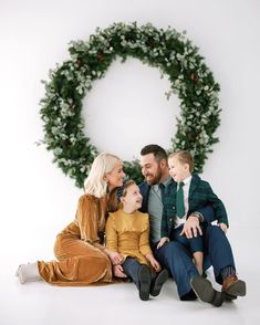 a family sitting in front of a christmas wreath