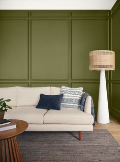 a living room with green walls and a white couch in front of a wooden table