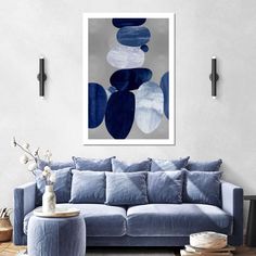 a living room with a blue couch and art work on the wall above it,