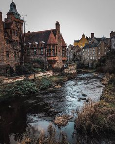 a river running through a small town next to tall brick buildings with towers on top