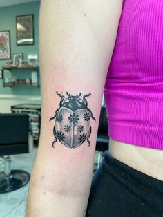 a lady bug tattoo on the left arm