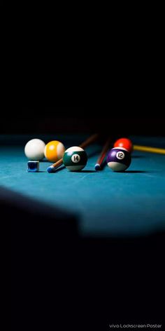 billiards balls and cues on a pool table in the dark, ready to play