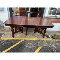 a large wooden table sitting in front of a storefront with yellow lines on the ground