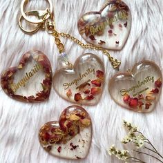 four heart shaped glass keychains with flowers on them sitting on a fur surface