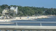 people are on the beach and in the water near some houses with trees around them