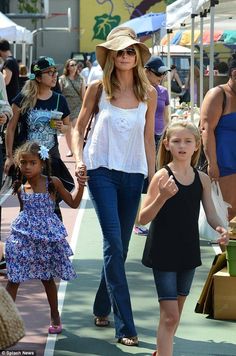 the mother and daughter are walking down the street with other people in the crowd behind them