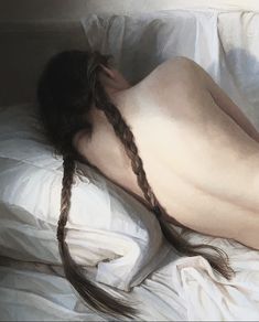 a naked woman laying on top of a bed covered in white sheets and braids