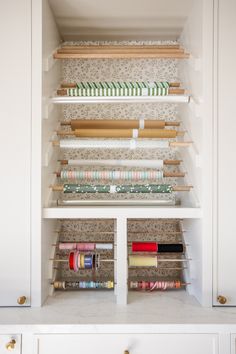 an organized craft room with white cabinets and shelves filled with different types of sewing supplies