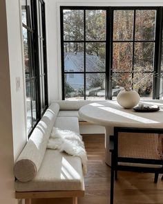 a white couch sitting in front of a window next to a table