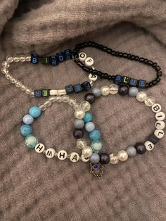 three beaded bracelets with words and beads on top of a gray fabric background