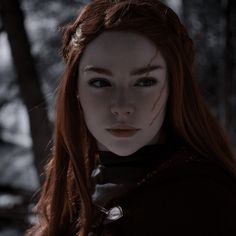 a woman with blood on her face standing in the woods