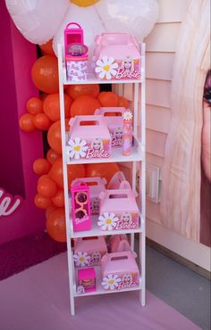 there is a shelf that has many pink and white baskets on it, with balloons in the background