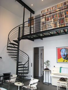 there is a spiral staircase in the living room with bookshelves on the wall