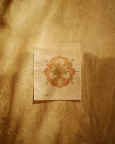 a piece of paper that is on top of a bed sheet with a flower design