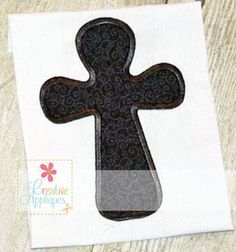 an iron - on patch with the shape of a cross in black and grey, sitting on top of a white piece of paper