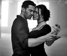 a man and woman are dancing together in an empty room with their arms around each other