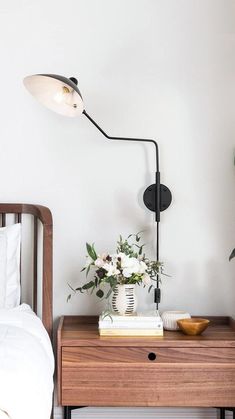 a bed with white sheets and pillows next to a lamp that is on top of a night stand