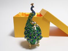 a peacock figurine sitting in front of a yellow box