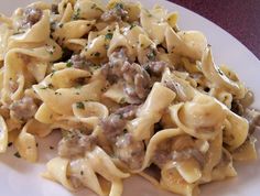 a white plate topped with pasta covered in meat and cheese sauce on top of a wooden table