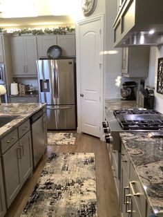 a kitchen with stainless steel appliances and granite counter tops, along with an area rug on the floor